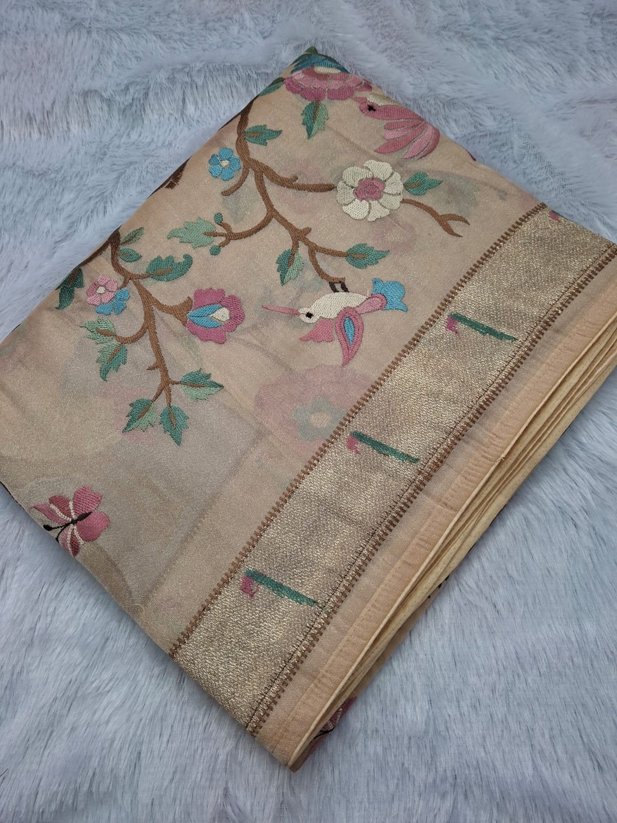 Beige pure tissue saree with bird and tree embroidery, folded