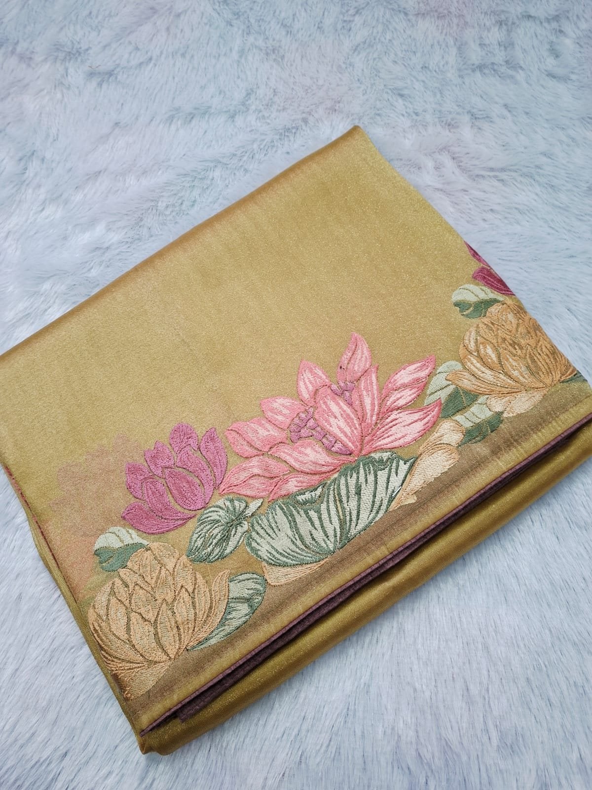 Gold pure tissue saree with a lotus embroidery border, folded